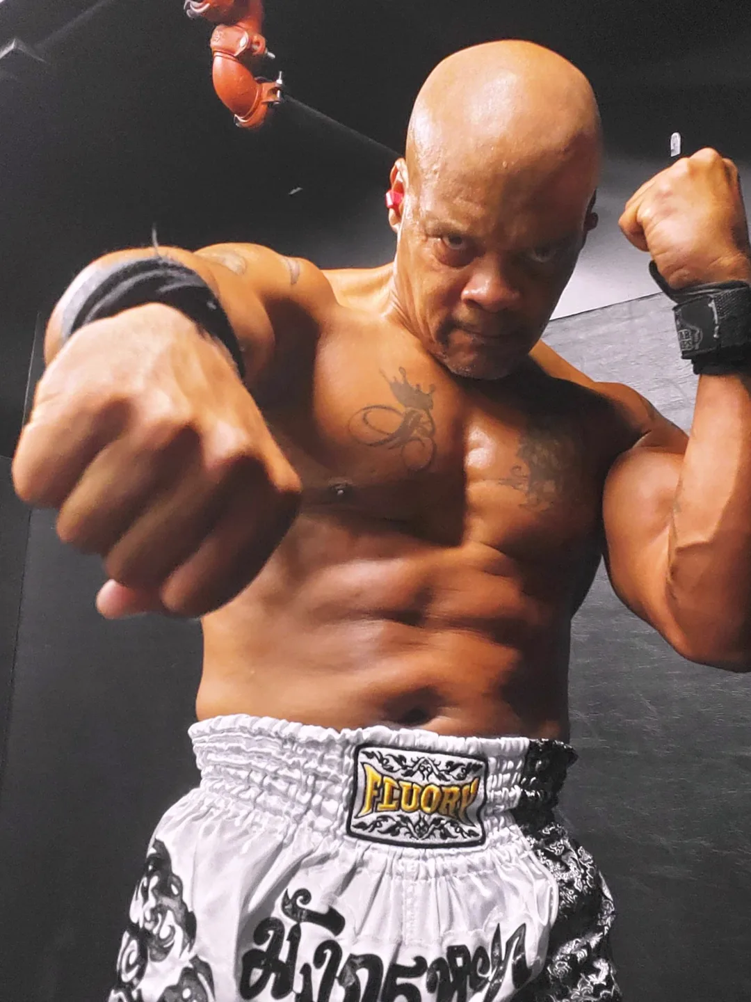 Coach Bizz throwing a jab straight at the camera in his Muay Thai shorts